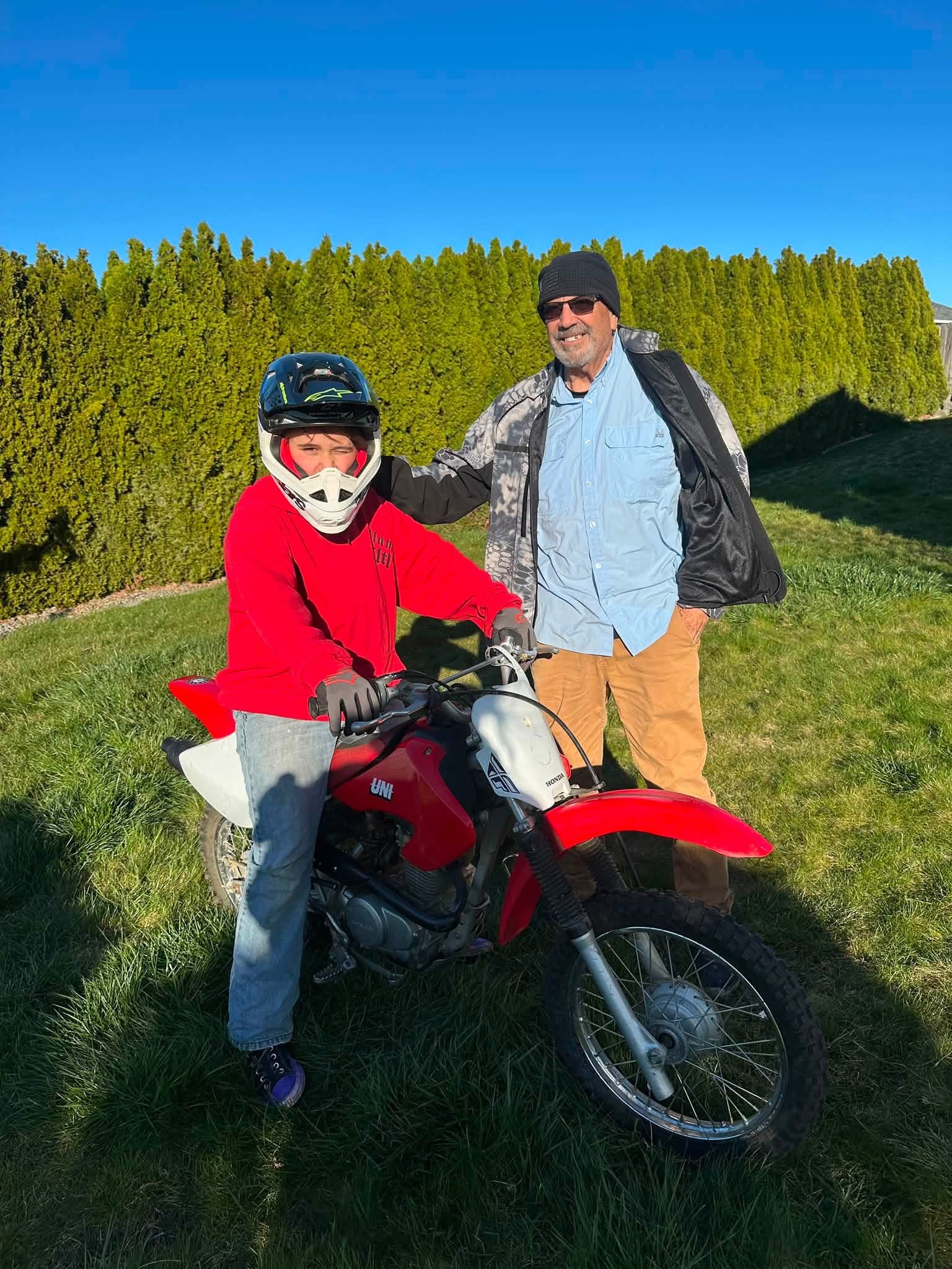 Glen standing beside his grandson on a motorcycle